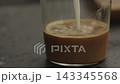 Pour milk into glass with shot of espresso 143345568