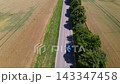 Aerial video of a car driving along a scenic rural road between farm fields  143347458