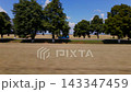 Aerial video showing a side view of a blue SUV driving along a beautiful road with trees at the side of the road and blue sky and in the background 143347459