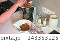 A woman grinds stewed vegetables using a meat grinder in her kitchen. She is making zucchini caviar with fresh ingredients and carefully following the steps 143353125