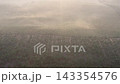Aerial view shows cleared land and dense forest below. Fog swirls over recently harvested land 143354576