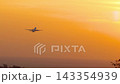 Passenger airplane climbing into golden sunset sky over sea 143354939