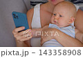 Close-up of mother holding son while looking at smartphone. Concept of phone addiction and early childhood exposure to smartphones. 143358908