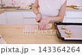 Cookies recipe. Baker work. Woman hand cut biscotti roll log dough with cranberry on home kitchen table placing treat on oven tray. 143364264