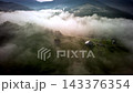 Aerial hyperlapse of dense morning fog rolling over mountain valley with houses 143376354
