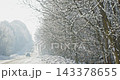 Car driving down a snowy rural road during a blizzard on a cold day 143378655