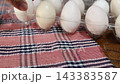 One white egg from a Silkie chicken. On a checkered mat. 143383587