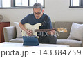 リビングでギターを弾く中高年男性 143384759