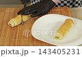 Chef serving baked puff pastry rolls with green pea filling and vegetables 143405231