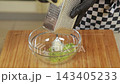 Chef grating hard cheese into green pea puree for pastry filling 143405233