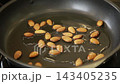 Almonds roasting in hot oil in a frying pan 143405235