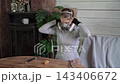 Woman putting on respirator and gloves for indoor renovation beside wooden table with cabinet and houseplant in rustic workshop room during daylight preparation 143406672