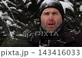 A frozen man buttons up his jacket in nature. 143416033