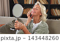 Love yourself. Beautiful old mature woman enjoying mirror reflection. Senior adult older lady looking at mirror confident happy on sofa at home. Woman doing daily morning beauty routine. Self love 143448260