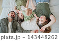 Happy family. Mother father two children daughters relaxing in bed at home indoor. Mom dad parents kids girls playing hugging having fun together. Family smiling laughing enjoying tender moment 143448262