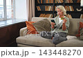 Happy middle aged woman shopping online with smartphone paying with credit card. Mature lady buying on Internet enter credit card details at home indoors. Online shopping delivery service ecommerce 143448270