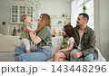 Happy family at home. Mother father two children daughters relaxing on sofa indoor. Mom dad parents baby girls kids relax playing having fun together. Family smiling laughing enjoying tender moment 143448296