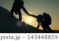 Hikers reaching out to one another climbing mountain peak. Teamwork businesspeople. Achieve your goal. Hikers climbing to summit success, silhouette climber. Business team victory. Mountain sun snow 143448859