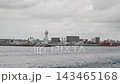 【船上からの風景】白い灯台がある防波堤と曇り空の港町の街並み（到着・出港） 143465168