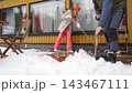Happy winter lifestyle moment as a couple clears fresh snow from a cozy home patio. Cold weather, soft daylight, teamwork and seasonal mood create a warm family atmosphere. 143467111