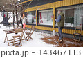 Happy winter lifestyle moment as a couple clears fresh snow from a cozy home patio. Cold weather, soft daylight, teamwork and seasonal mood create a warm family atmosphere. 143467113