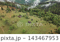 Aerial view of remote cabins and grazing animals in a misty mountain valley, Aerial nature footage presents remote travel ecology and peaceful wilderness 143467953