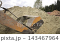 Concrete mixer loader fills its front bucket with sand at a work site, Close view of a machine collecting fine aggregate from an outdoor pile 143467964