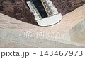 Steep concrete face of Hoover Dam drops toward water and machinery below, High angle footage reveals monumental engineering in the desert canyon 143467973