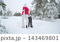Winter walk in snowy forest. Family lifestyle moment with child and adult holding hands, warm clothing, holiday mood, peaceful nature, love and togetherness outdoors. 143469801