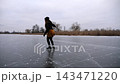 Female skater skating on ice surface at cloudy day. Sportswoman shod in figure skates training at frozen river or lake. Woman improving skills and having active leisure at winter cold weather. Slow mo 143471220