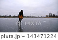 Female skater skating on ice surface at cloudy day. Sportswoman shod in figure skates training at frozen river or lake. Woman improving skills and having active leisure at winter cold weather. Slow mo 143471224