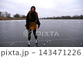 Young woman shod in figure skates sliding on ice rink at winter nature. Girl skating on frozen river at cloudy day. Lady enjoying sport and improving skills at lake in cold weather. Close up Slow mo 143471226
