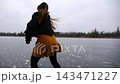 Girl skating on frozen river or lake at cloudy day. Young woman shod in figure skates sliding on ice rink at nature. Sportswoman training at winter cold weather. Active leisure at wintertime. Slow mo 143471227
