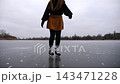 Young woman shod in figure skates sliding on ice outdoor. Sportswoman skating on frozen river or lake. Girl enjoying sport and having active leisure at winter cold weather. Close up Slow motion 143471228