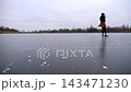 Female skater training rotation skills on frozen river. Young girl shod in figure skates sliding on ice rink outdoor. Sportswoman skating at lake in cold weather. Active leisure at freeze winter day 143471230
