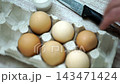 takes a few eggs from the package 143471424