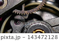 Extreme macro shot of vintage mechanical watch movement showing blue hairspring, oscillating balance wheel, and ruby jewel bearings 143472128