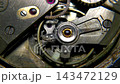 Extreme macro shot of mechanical watch balance wheel oscillating with hairspring and ruby jewel bearing 143472129