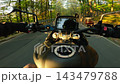 POV motorcycle ride on an asphalt road through an autumn forest at sunset, with golden foliage, warm evening light and motion blur creating a dynamic sense of speed and travel. 143479788