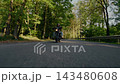 Dynamic tracking shot of a motorcyclist riding through a winding forest road, filmed from the front with fast camera movement, motion blur and a strong sense of speed and adventure. 143480608