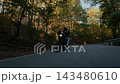 Dynamic tracking shot of a motorcyclist riding through a winding forest road, filmed from the front with fast camera movement, motion blur and a strong sense of speed and adventure. 143480610