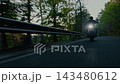 Dynamic tracking shot of a motorcyclist riding through a winding forest road, filmed from the front with fast camera movement, motion blur and a strong sense of speed and adventure. 143480612