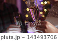 Loving couple dances with champagne glasses at New Year party, close-up. Young woman. man move while flashing strobe lights, warm garland lights decorate cheerful friendly disco celebration. 143493706