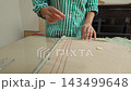 Woman carefully pinning fabric and sewing by hand at home workshop. 143499648