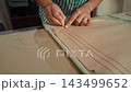Tailor woman carefully marking fabric with chalk and ruler in a bright workshop setting 143499652