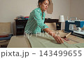 Talented tailor woman working in her workshop, smoothing fabric and pinning paper patterns. 143499655