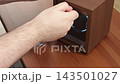 A hand opening a modern wooden watch winder box on a desk, representing luxury accessory storage and automatic timekeeping maintenance for a collection in a sophisticated home setting 143501027
