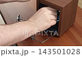 A hand placing a luxury watch into a wooden automatic winder box, conveying precise maintenance for mechanical timepieces in a modern home office setting for refined collectors 143501028