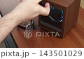 A hand placing a luxury leather wristwatch into a wooden automatic winder, capturing the sophisticated maintenance process for high-end mechanical timepieces in a modern home 143501029