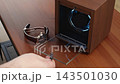 A hand opening a wooden watch winder box to remove an automatic timepiece, showcasing the meticulous care and maintenance required for luxury mechanical accessories in a home study 143501030